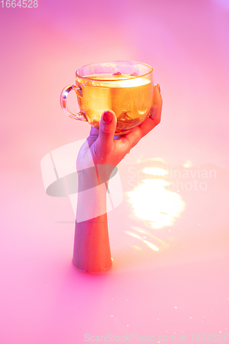 Image of Close up female hand gesturing from the milk bath with soft glowing in neon light