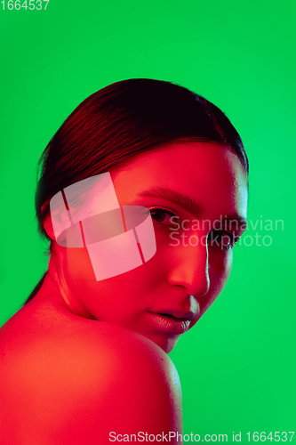 Image of Beautiful east woman close up portrait isolated on green background in red neon light