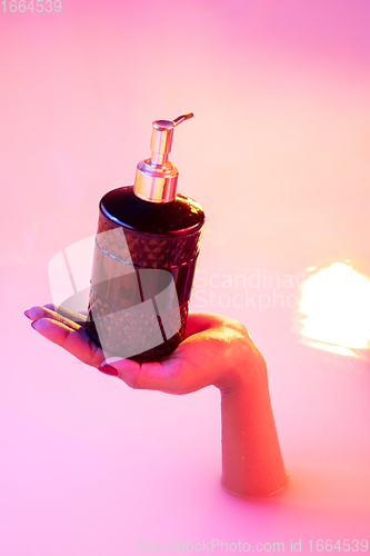 Image of Close up female hand gesturing from the milk bath with soft glowing in neon light