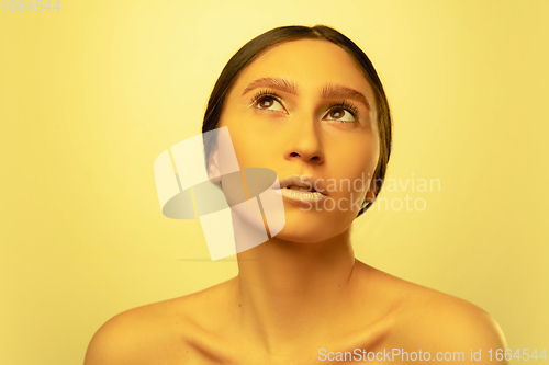 Image of Beautiful east woman portrait isolated on yellow studio background in neon light, monochrome