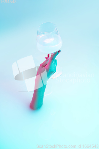 Image of Close up female hand gesturing from the milk bath with soft glowing in neon light