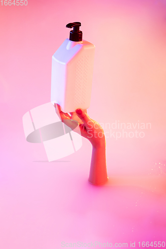 Image of Close up female hand gesturing from the milk bath with soft glowing in neon light