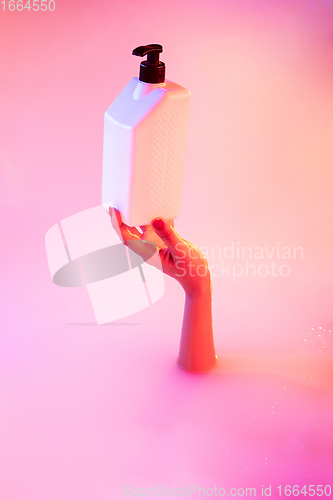 Image of Close up female hand gesturing from the milk bath with soft glowing in neon light