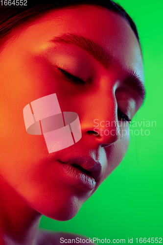 Image of Beautiful east woman close up portrait isolated on green background in red neon light