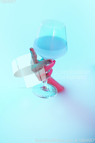 Image of Close up female hand gesturing from the milk bath with soft glowing in neon light