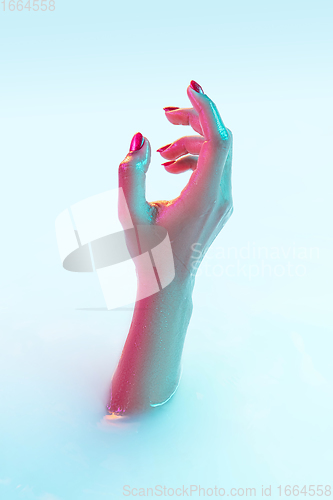 Image of Close up female hand gesturing from the milk bath with soft glowing in neon light