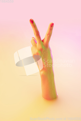 Image of Close up female hand gesturing from the milk bath with soft glowing in neon light