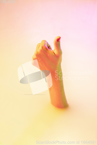 Image of Close up female hand gesturing from the milk bath with soft glowing in neon light