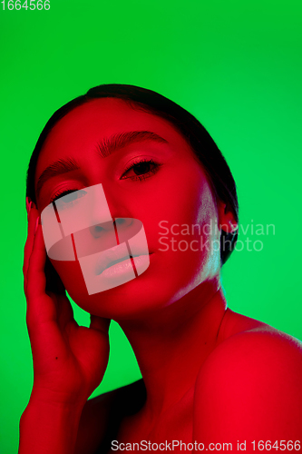 Image of Beautiful east woman close up portrait isolated on green background in red neon light