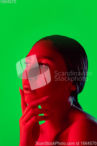 Image of Beautiful east woman close up portrait isolated on green background in red neon light