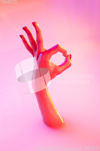 Image of Close up female hand gesturing from the milk bath with soft glowing in neon light