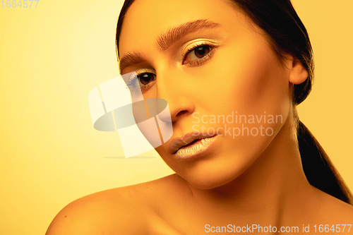 Image of Beautiful east woman portrait isolated on yellow studio background in neon light, monochrome