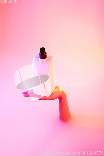 Image of Close up female hand gesturing from the milk bath with soft glowing in neon light