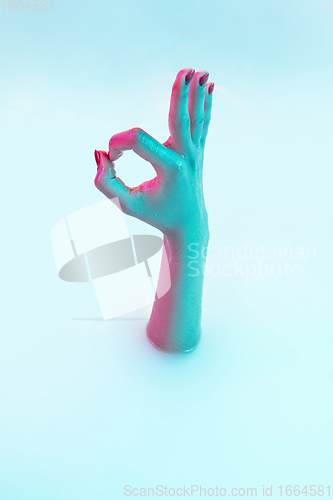 Image of Close up female hand gesturing from the milk bath with soft glowing in neon light