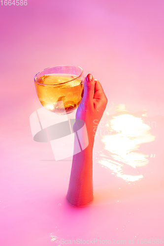 Image of Close up female hand gesturing from the milk bath with soft glowing in neon light