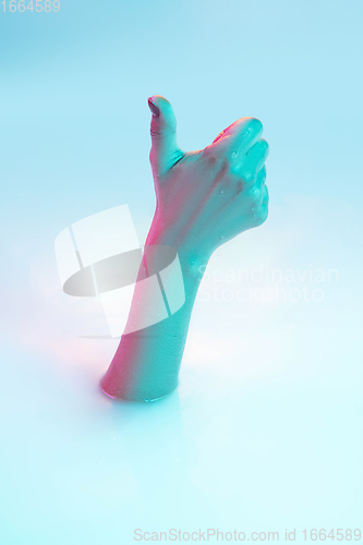 Image of Close up female hand gesturing from the milk bath with soft glowing in neon light