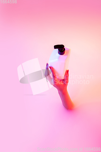 Image of Close up female hand gesturing from the milk bath with soft glowing in neon light