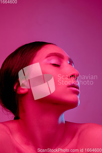 Image of Beautiful east woman portrait isolated on pink studio background in neon light, monochrome