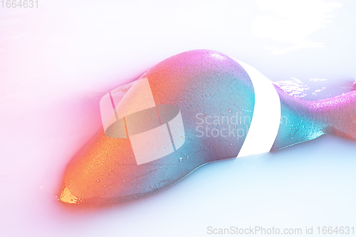 Image of Close up female body in the milk bath with soft glowing in neon light