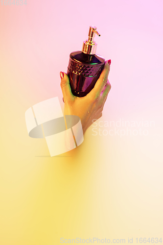 Image of Close up female hand gesturing from the milk bath with soft glowing in neon light