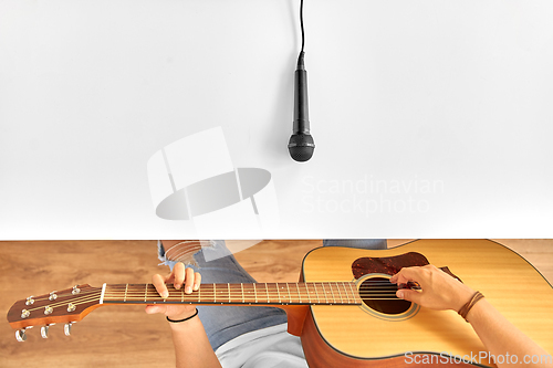 Image of man with microphone on table playing guitar