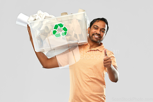 Image of smiling young indian man sorting paper waste