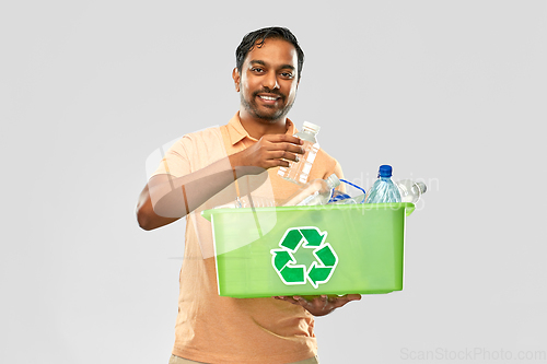 Image of smiling young indian man sorting plastic waste