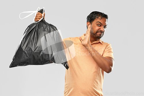 Image of indian man holding stinky trash bag