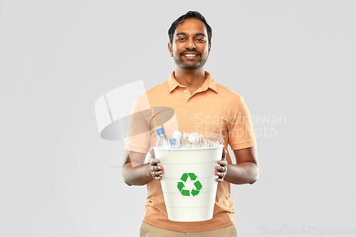 Image of smiling young indian man sorting plastic waste