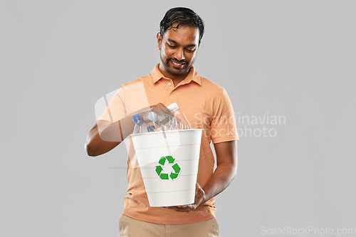 Image of smiling young indian man sorting plastic waste