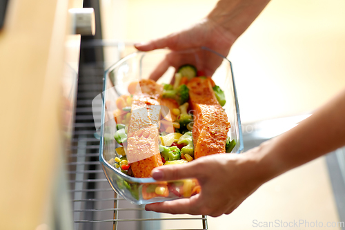 Image of woman cooking food in oven at home kitchen