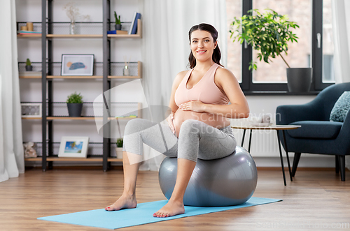 Image of pregnant woman exercising on fitness ball at home