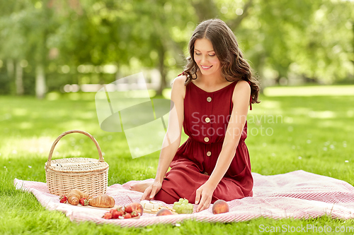 Image of happy woman with food and picnic basket at park