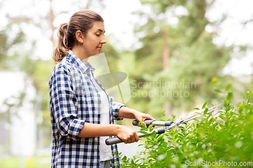 Image of woman with pruner cutting branches at garden