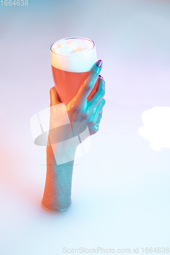 Image of Close up female hand gesturing from the milk bath with soft glowing in neon light