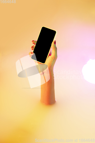 Image of Close up female hand gesturing from the milk bath with soft glowing in neon light