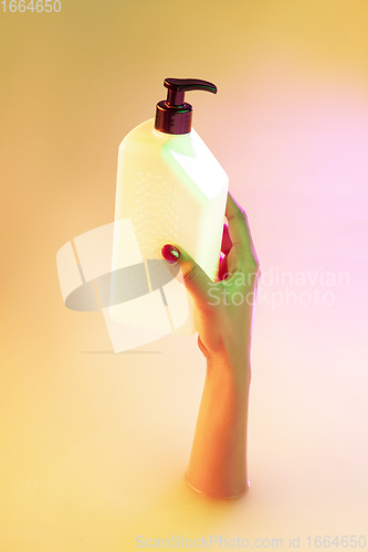 Image of Close up female hand gesturing from the milk bath with soft glowing in neon light