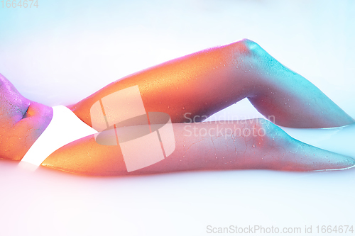 Image of Close up female body in the milk bath with soft glowing in neon light