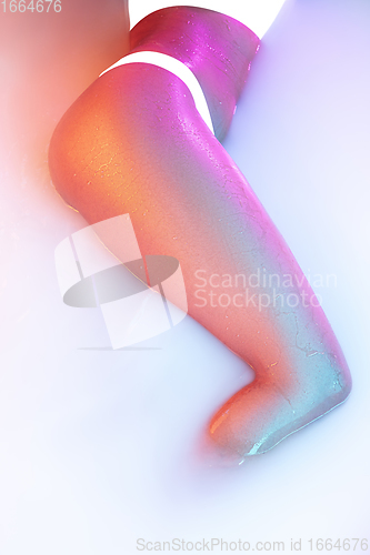 Image of Close up female body in the milk bath with soft glowing in neon light