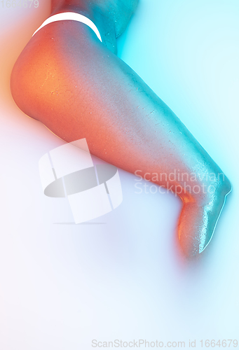 Image of Close up female body in the milk bath with soft glowing in neon light