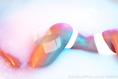 Image of Close up female body in the milk bath with soft glowing in neon light