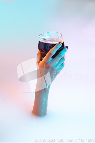 Image of Close up female hand gesturing from the milk bath with soft glowing in neon light