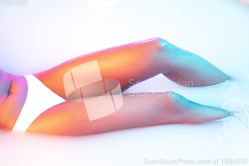 Image of Close up female body in the milk bath with soft glowing in neon light