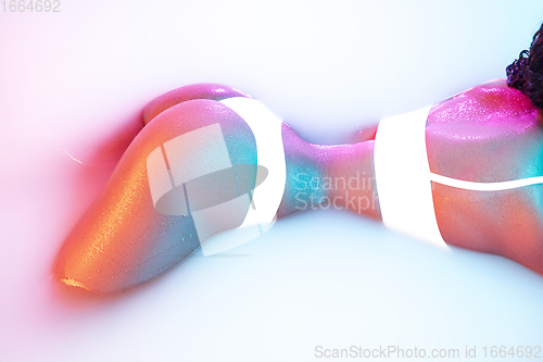 Image of Close up female body in the milk bath with soft glowing in neon light