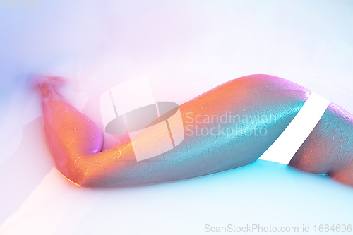 Image of Close up female body in the milk bath with soft glowing in neon light