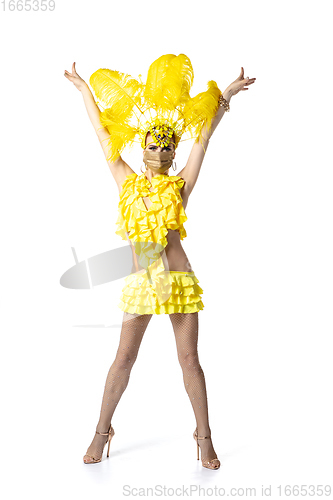 Image of Beautiful young woman in carnival, stylish masquerade costume with feathers dancing on white studio background.