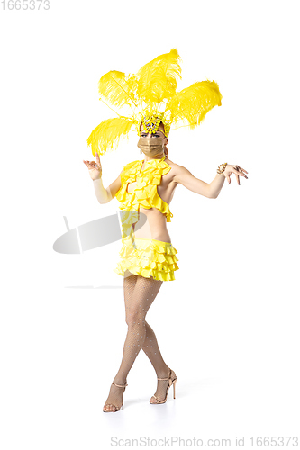 Image of Beautiful young woman in carnival, stylish masquerade costume with feathers dancing on white studio background.