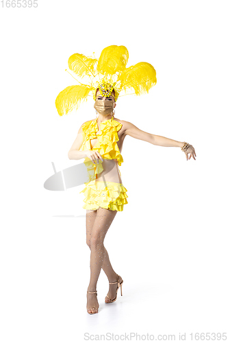 Image of Beautiful young woman in carnival, stylish masquerade costume with feathers dancing on white studio background.