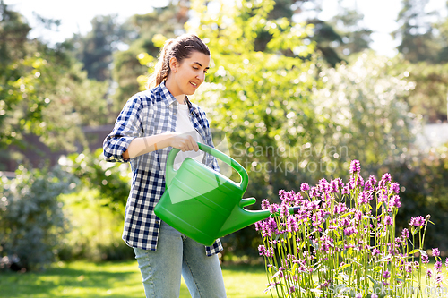 Image of young woman watering flowers at garden