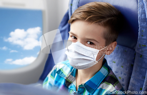 Image of boy in medical mask travelling by plane